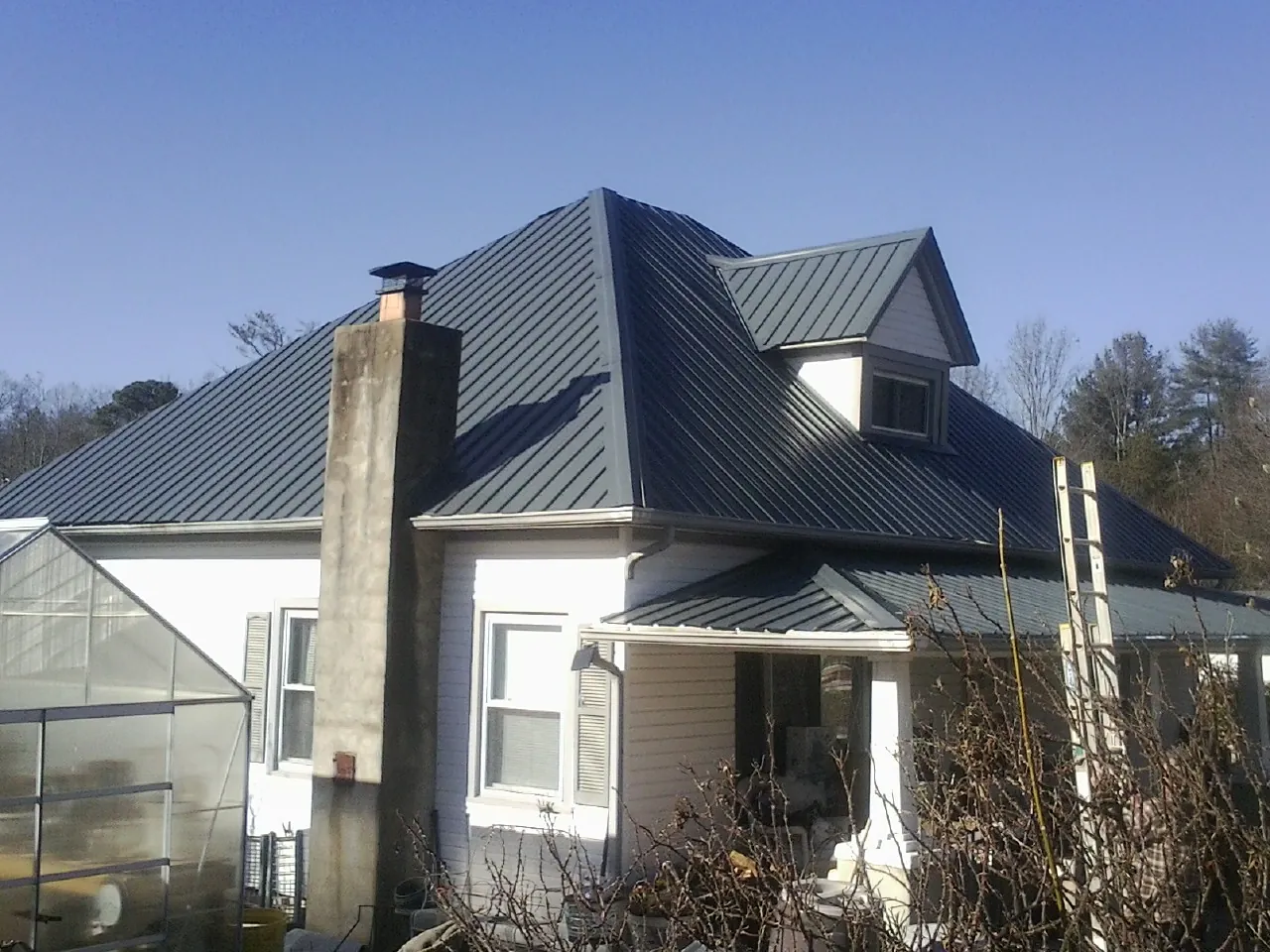 Dark blue standing seam metal roof on a white farmhouse with dormer — Slate & Tile Roof Repair by Roofing Brothers in Beech Bottom