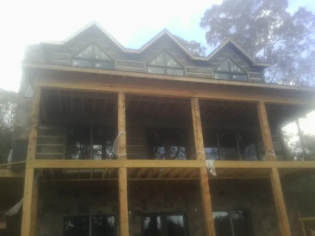 Dormers and porch framing on a large log home under construction — Roof Coating work by our crew in Beech Bottom