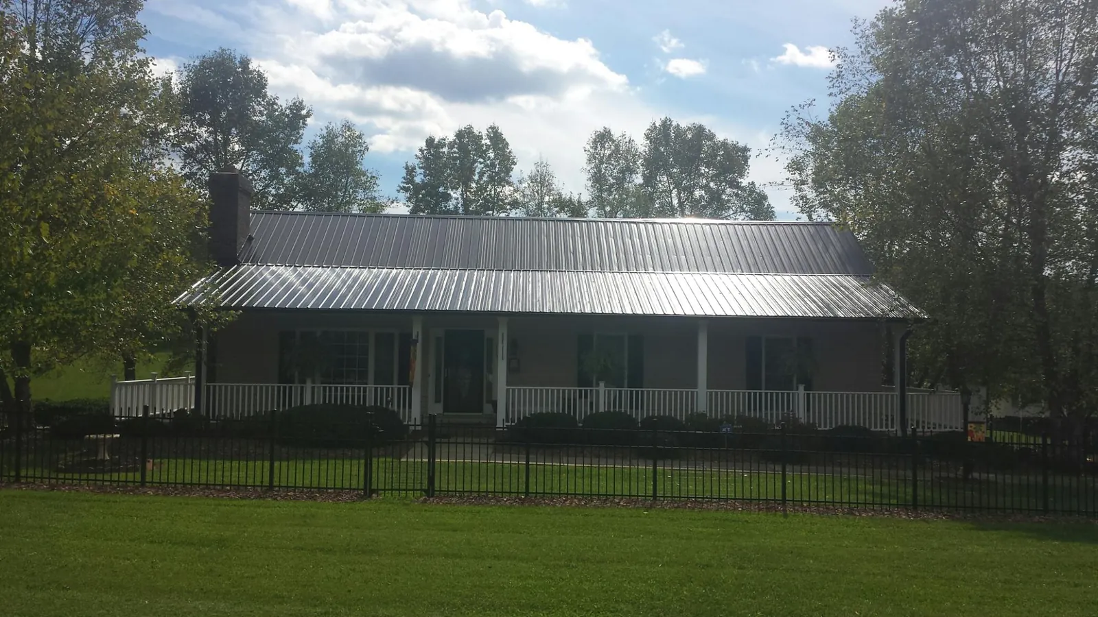 Gray metal roof on a brick ranch with a full width front porch — Gutter Guard Installation work by our crew in Beech Bottom