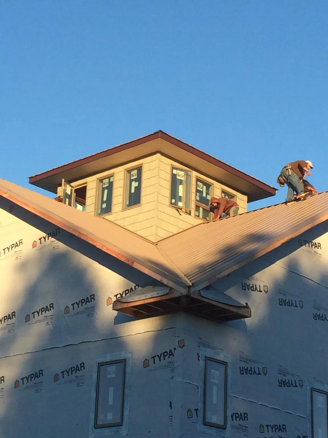 Roofers working around a rooftop cupola on a new metal roof at sunset — Roof Waterproofing in Beech Bottom by Roofing Brothers